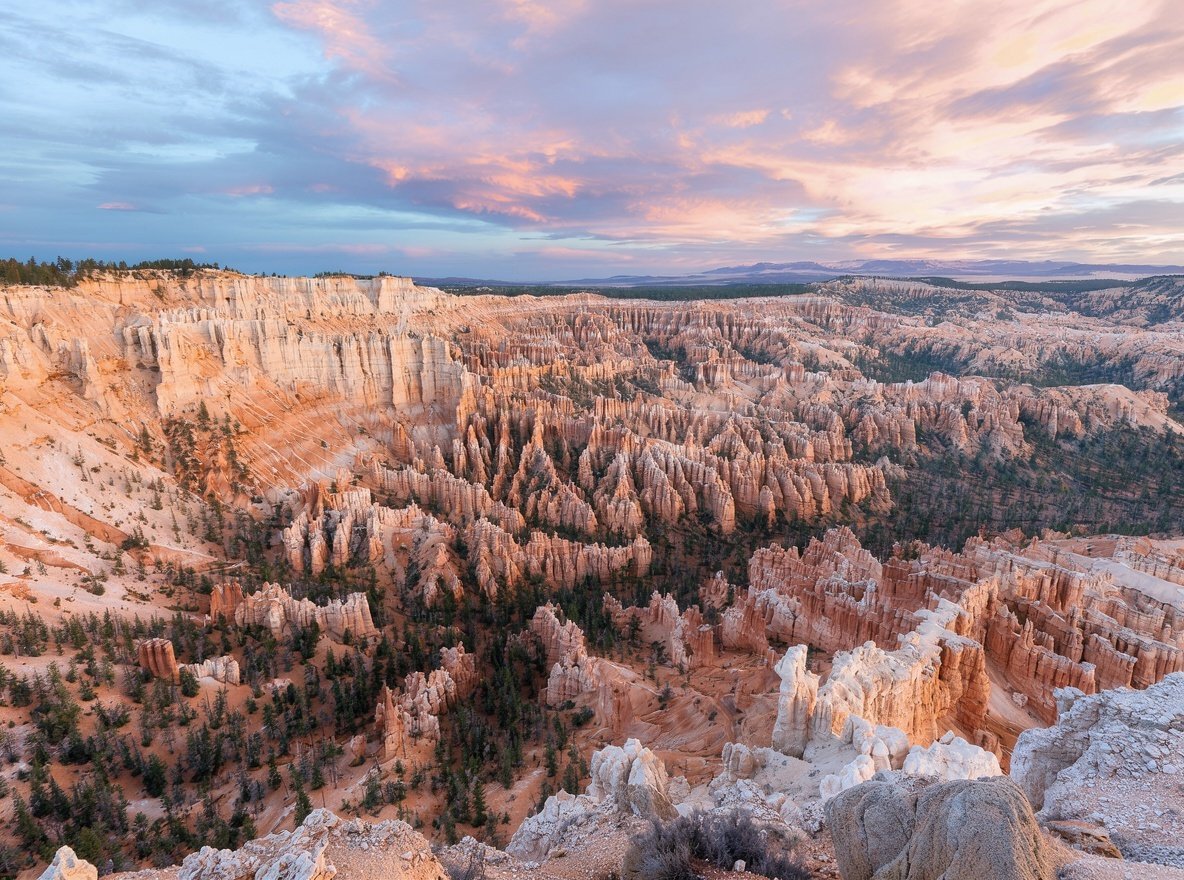 Orange and cream limestone hoodoos in Bryce Canyon dusted with frost at sunrise