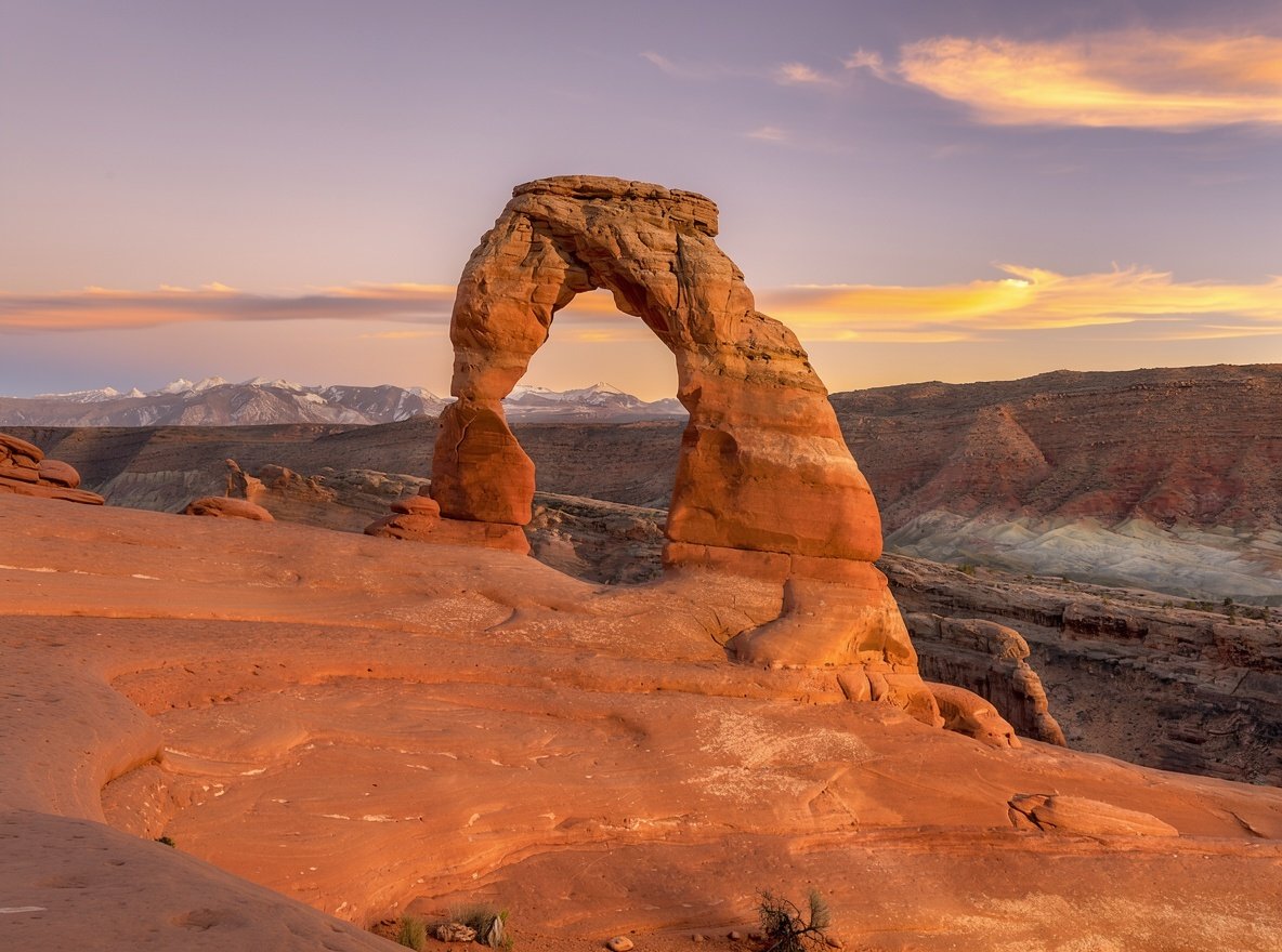 Delicate Arch standing on bare sandstone at sunset in Arches National Park, Utah
